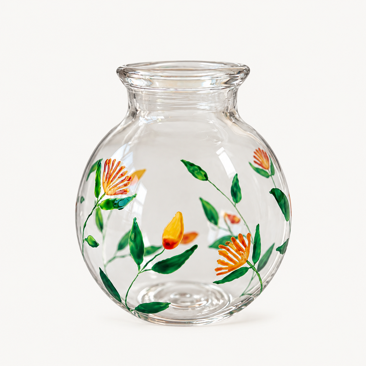 A clear hand blown glass vase with a rounded body and short flared neck, decorated with hand-painted green leaves and orange flowers with yellow centers, Alara london