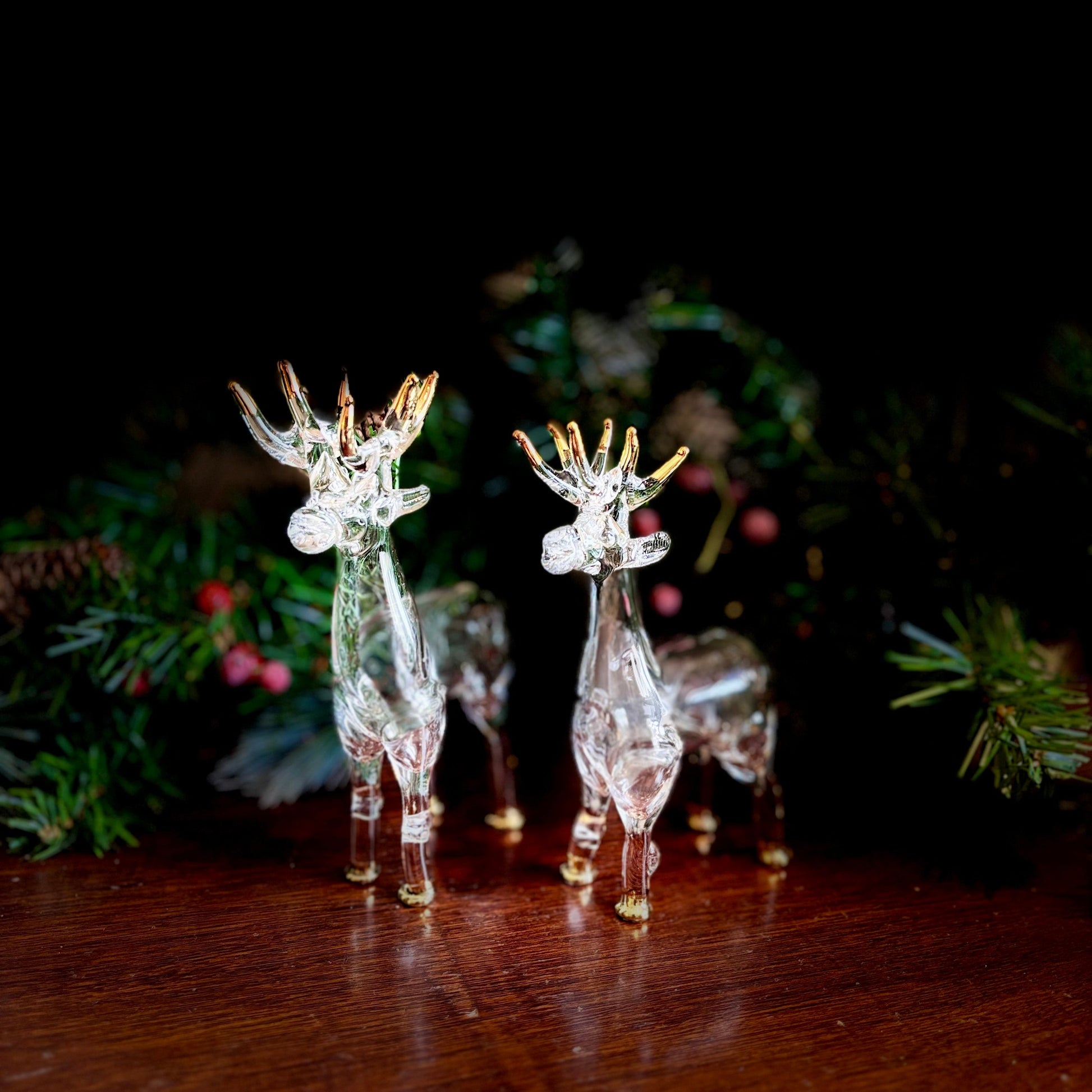 Transparent glass reindeer figurines on a wooden surface with a dark background