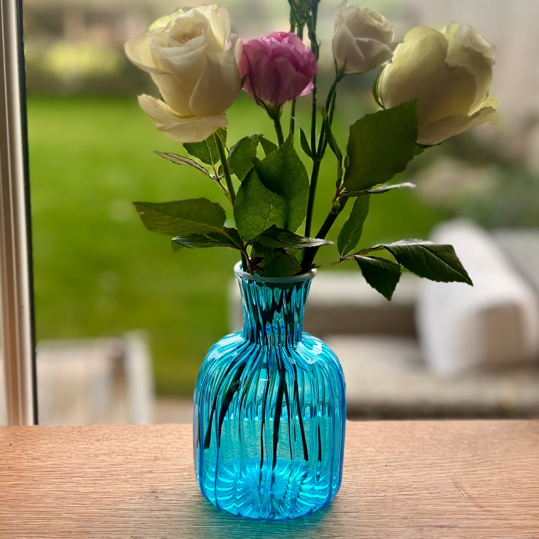 Blue  ribbed vase with flowers .